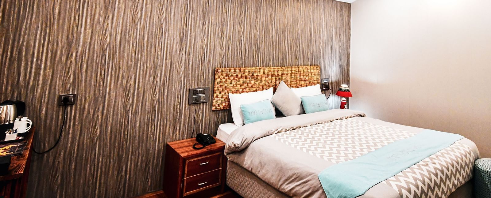 image of the standard room featuring a double bed in the corner with wooden flooring - The Tattva Boutique Resort
