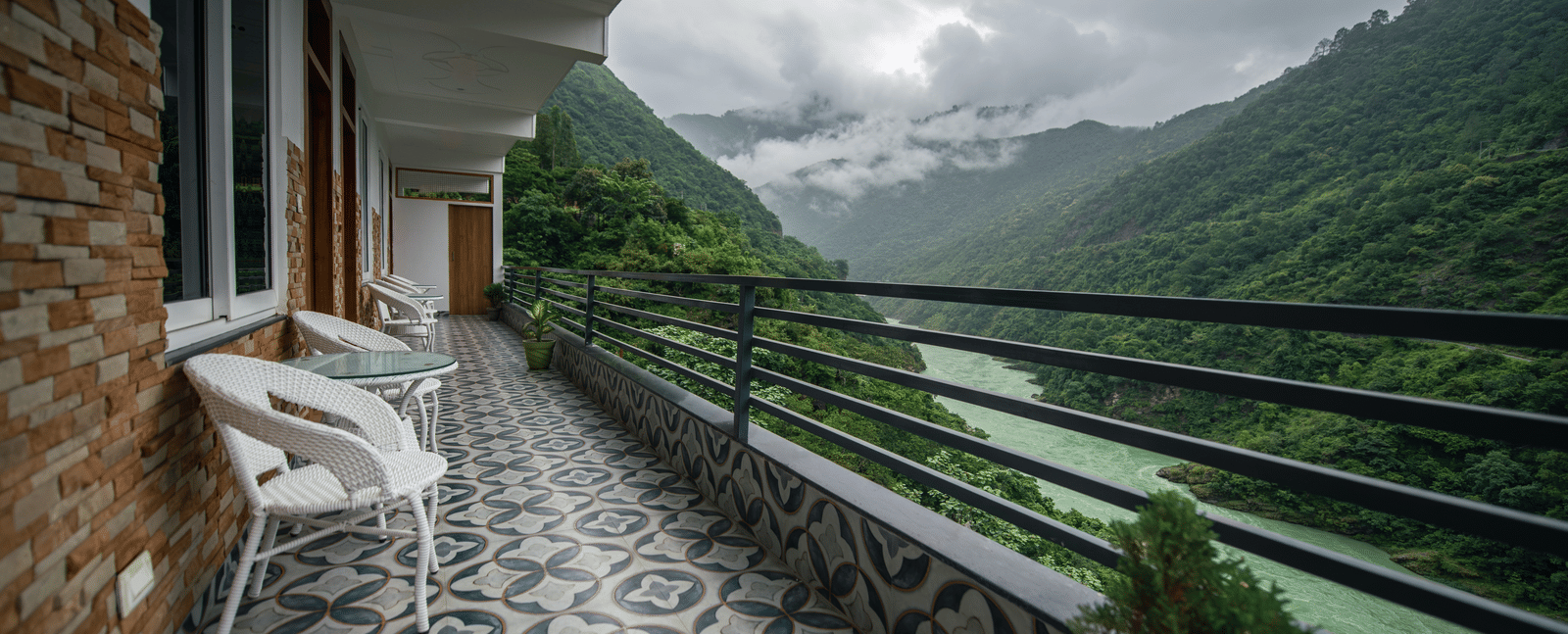 A balcony of a Deluxe Room at The Tattva Devaprayag with a view of the mountains and the river.