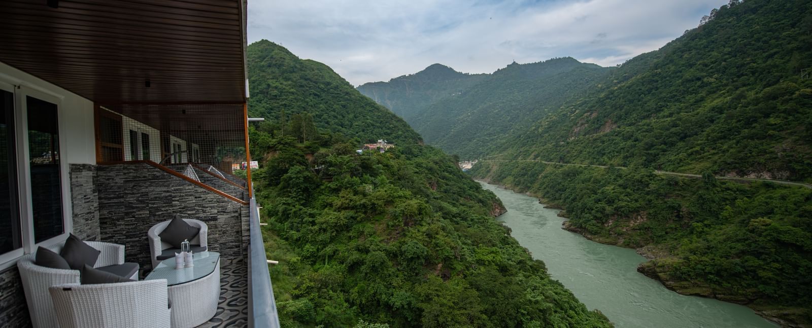 A balcony in the executive room at The Tattva Devaprayag with a view of the mountains and the river.