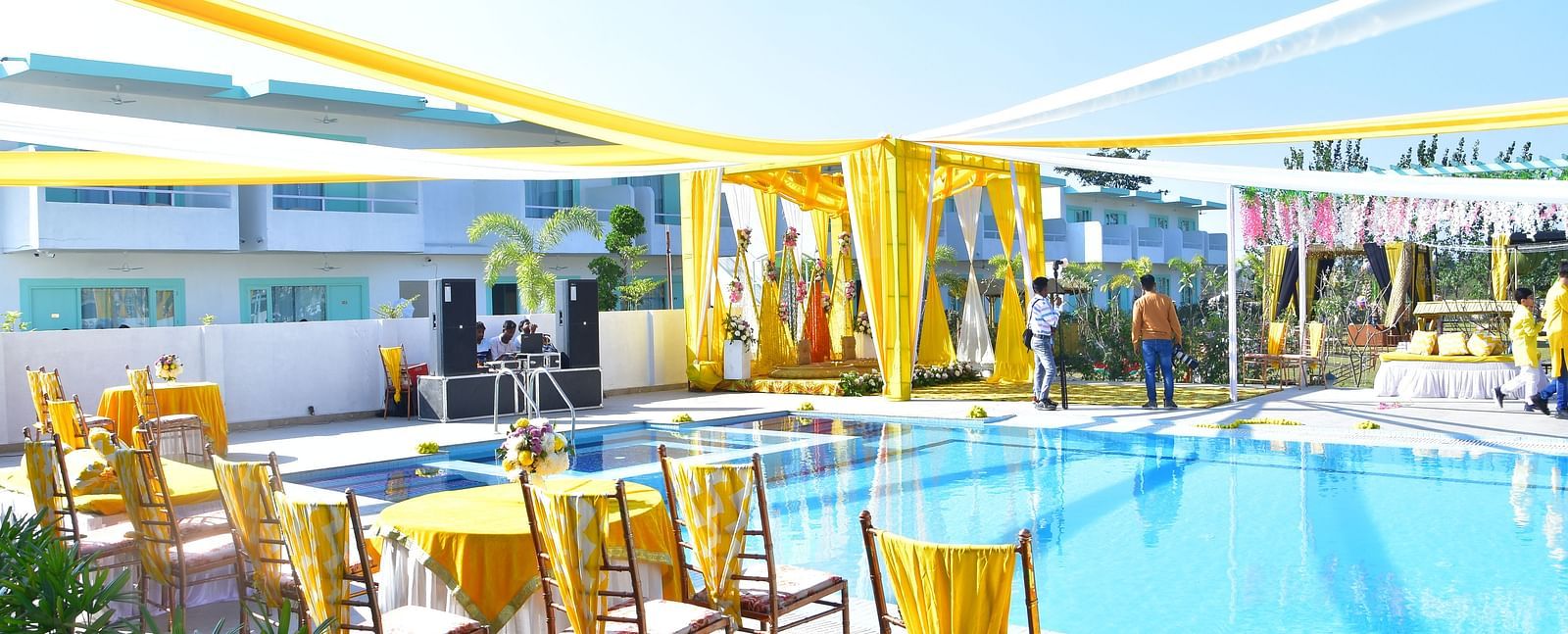 Poolside wedding seating arrangement with bright yellow drapery at Vedikant Resorts The Mallard Corbett.