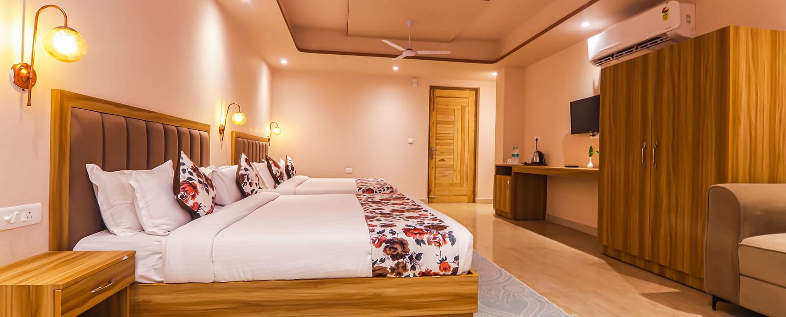 A modern bedroom at Vedikant Resorts The Mallard Corbett features beds, a seating area, and wooden furniture.
