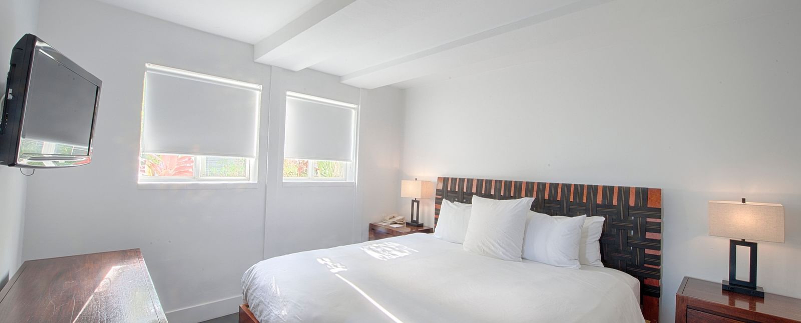 Bedroom at Casa Morada featuring a white bed, wooden furniture, and a wall-mounted TV.