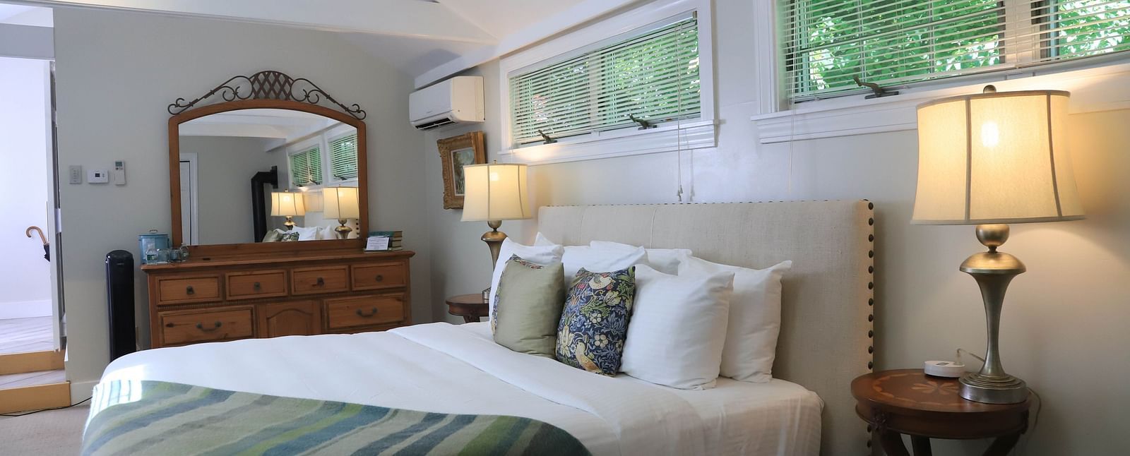 Hotel bedroom with green throw blanket and dresser at Hartstone Inn.