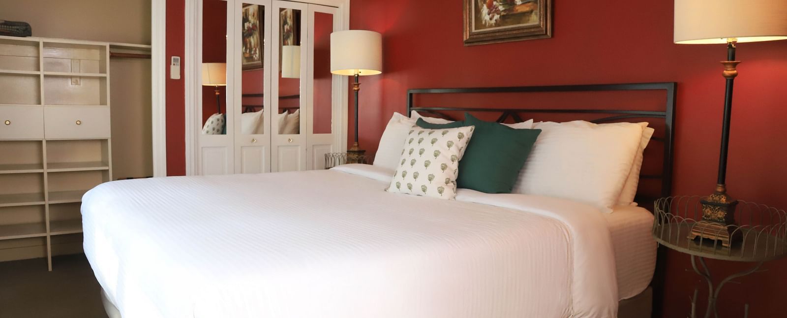 Hotel room with red walls, bed, and a lamp beside the bed at Hartstone Inn.