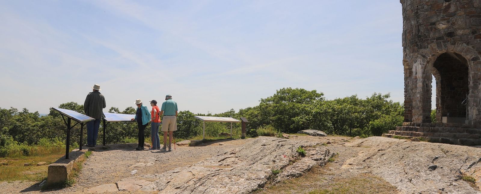 Visitors standing near a stone structure on a grassy hill near Hartstone Inn.