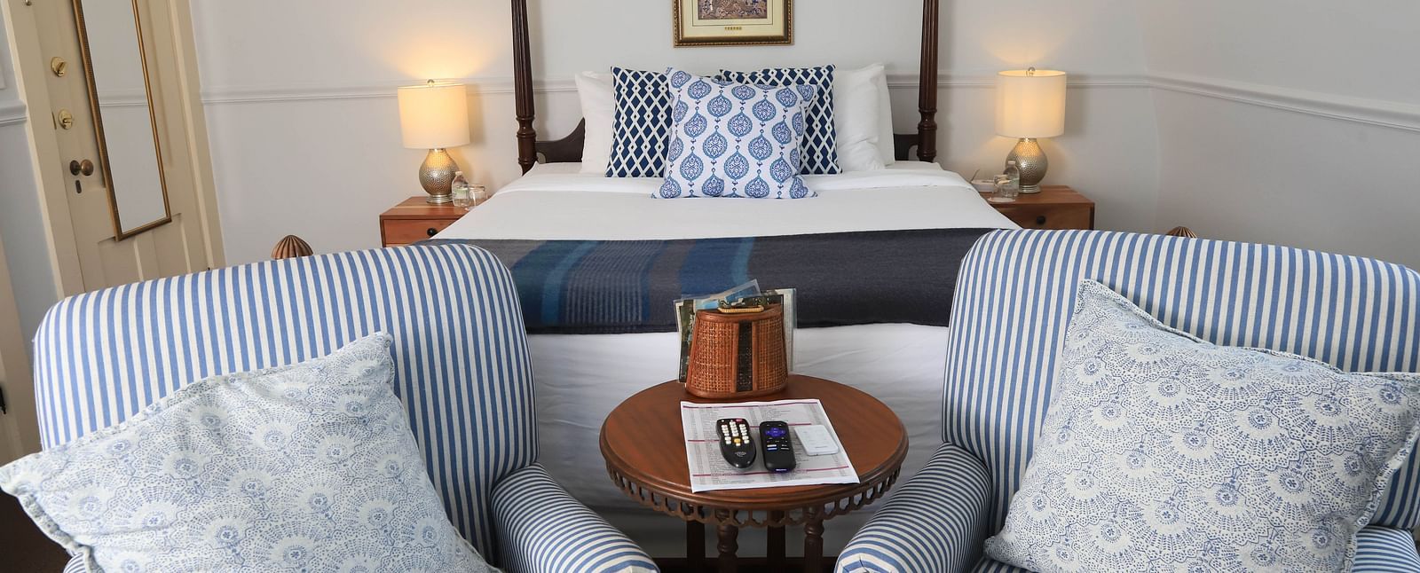 Seating area with striped chairs, tray table and showcasing a king size bed in the background at Hartstone Inn