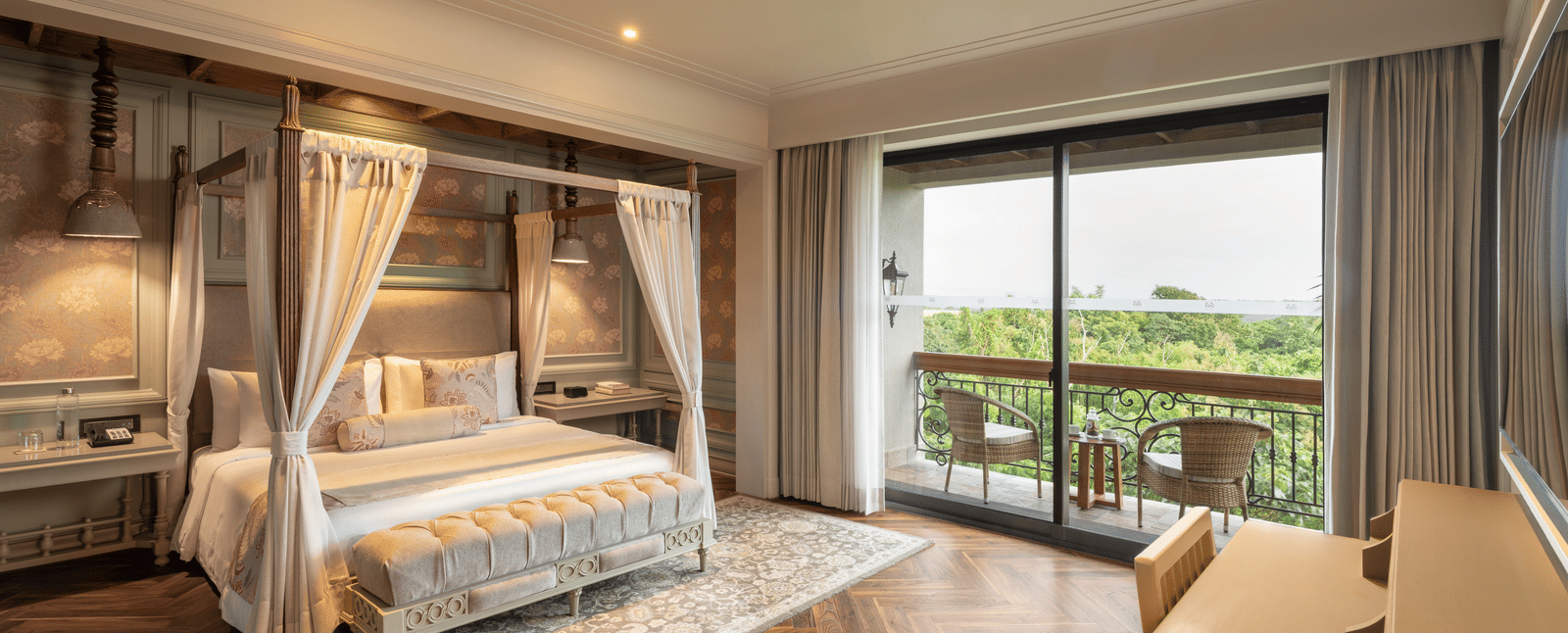 Full-view shot of the bedroom at the Evren Suite featuring wooden flooring and a balcony that opens to the verdant views of the frest at The Evren, Vagator.