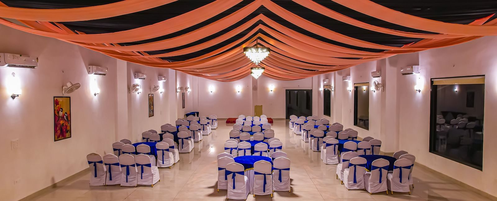 An indoor dining area at Vedikant Resorts The Mallard Corbett features tables and chairs under a decorated ceiling with lighting.