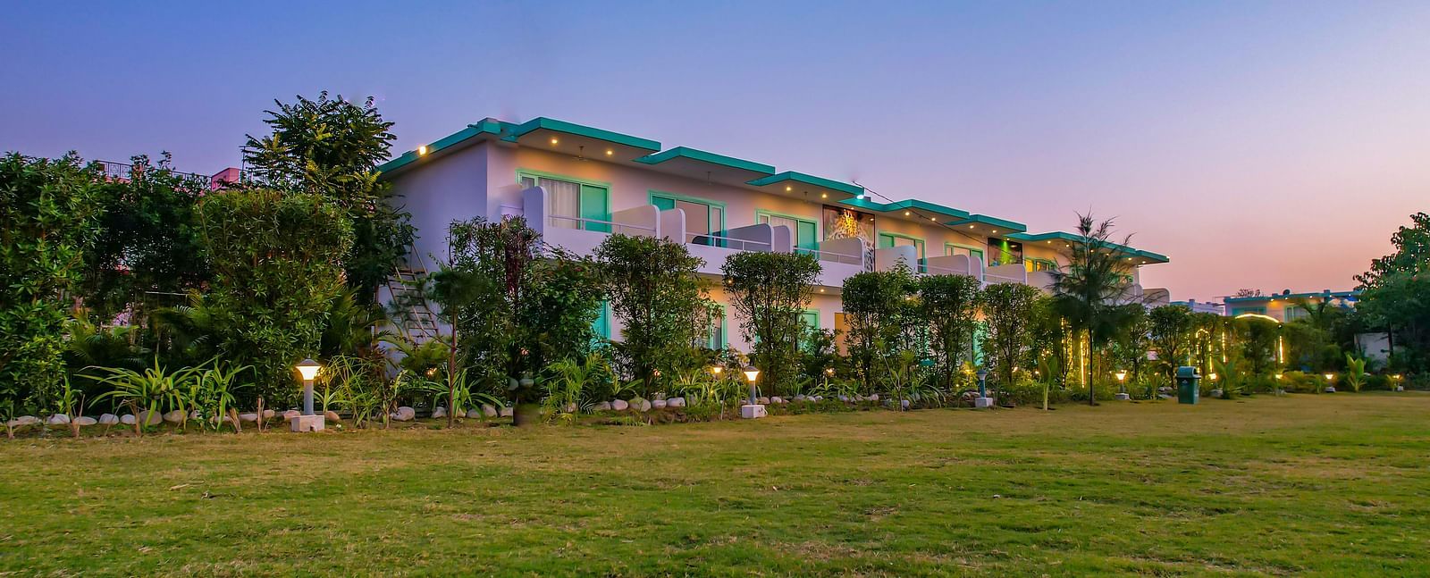 View of Vedikant Resorts The Mallard Corbett at twilight showcases the buildings and open grassy area.