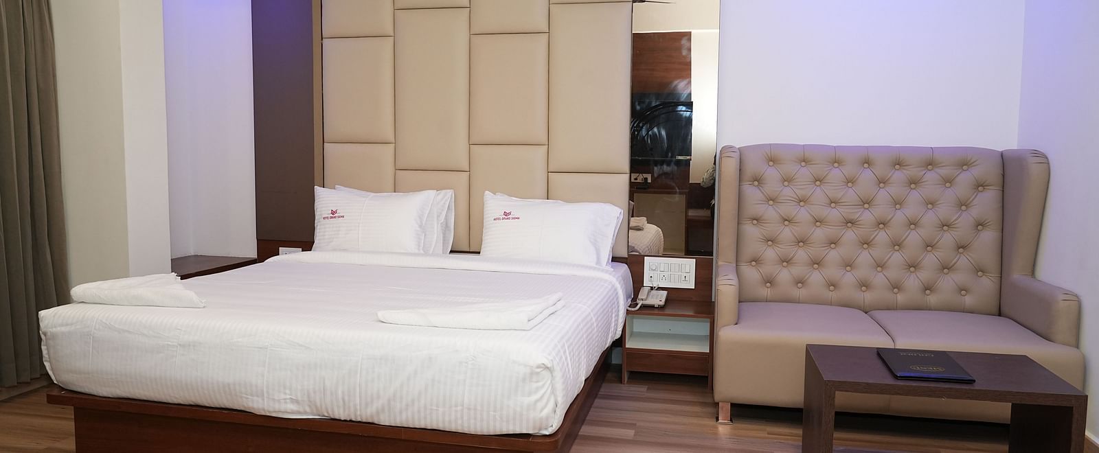 a suite room with a double bed and a couch featuring a small coffee table in front of it - Hotel Grand Sigma