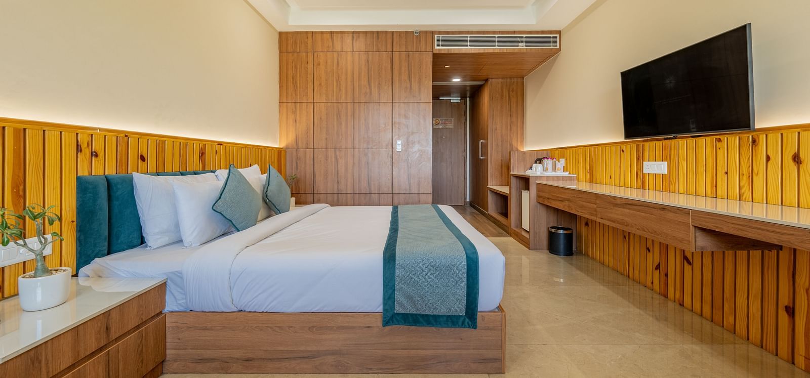 Modern room with king bed, flat-screen TV, and wooden decor accents in an executive king room at Hotel Highway, Bagru.