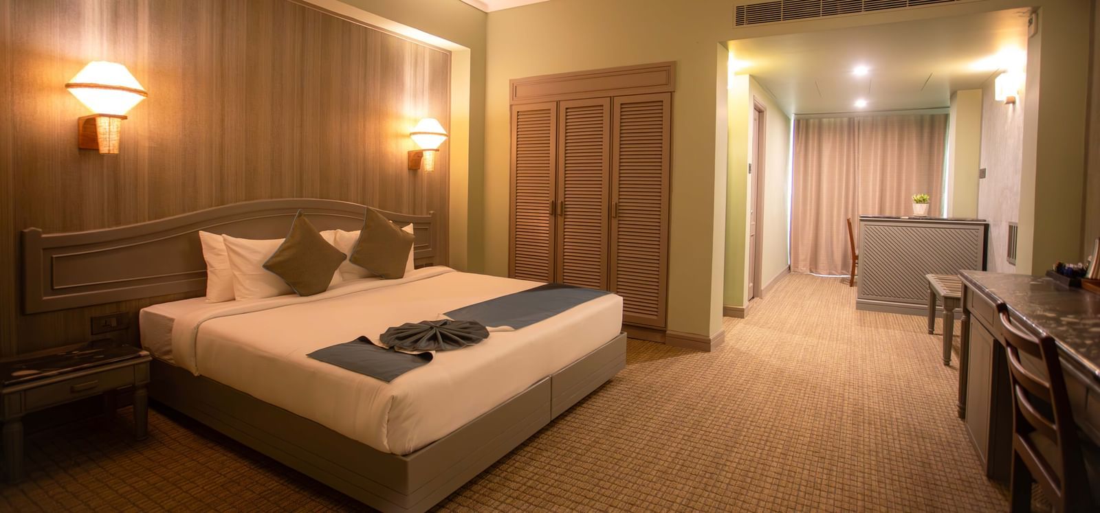  A suite at Shilton International, Kochi, with a large bed, sitting area, and ample storage.