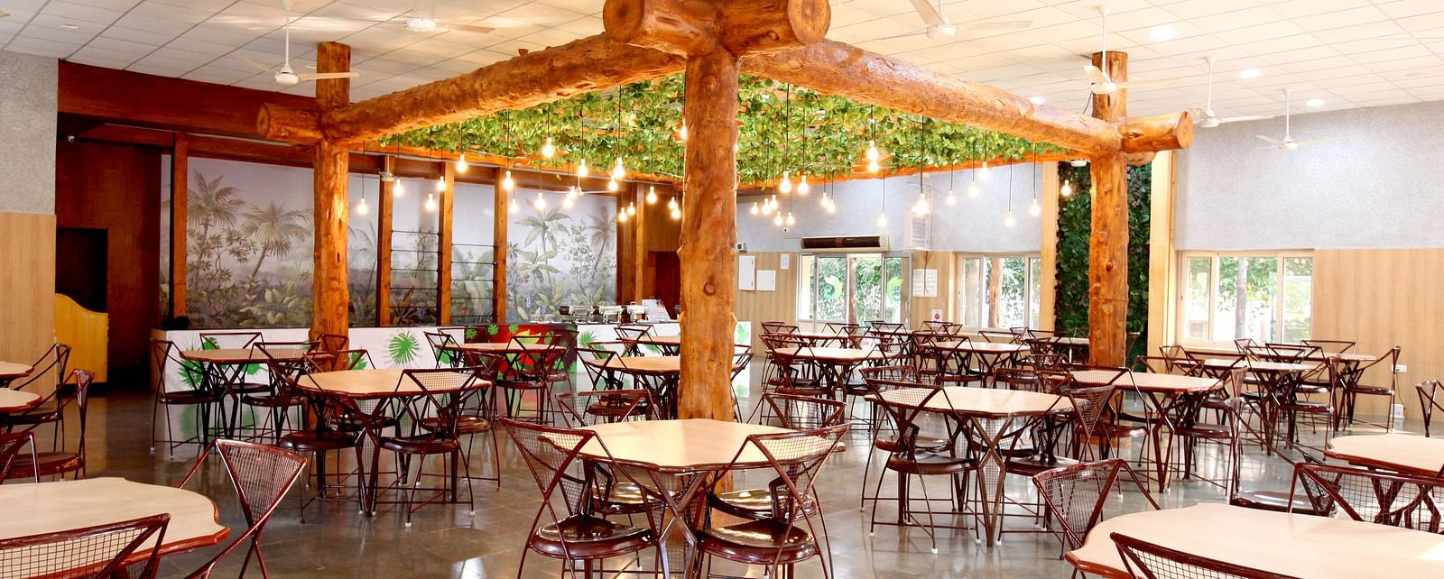 An elaborate seating arrangement at Greens Inn Restaurant featuring wooden furnishing and lit bulbs hanging from the ceiling at Greens Inn - Cozy Dining in Hyderabad.