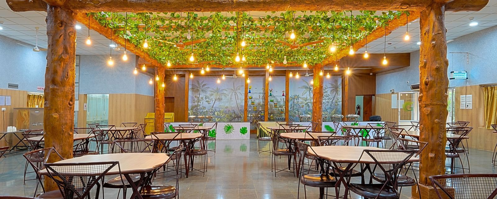 A well-lit restaurant with tables and chairs and light bulbs hanging from the ceiling at Greens Inn - Best Dining Experience in Hyderabad.