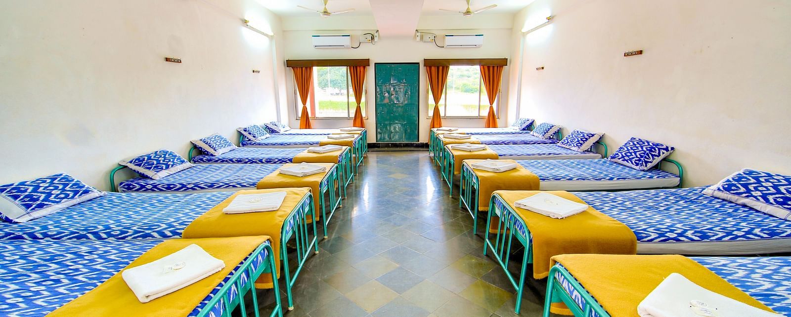 Multiple chairs around the circumference of long rectangular tables for dining at Hotel Sahara - Dining Area in Ramoji Film City, Hyderabad.
