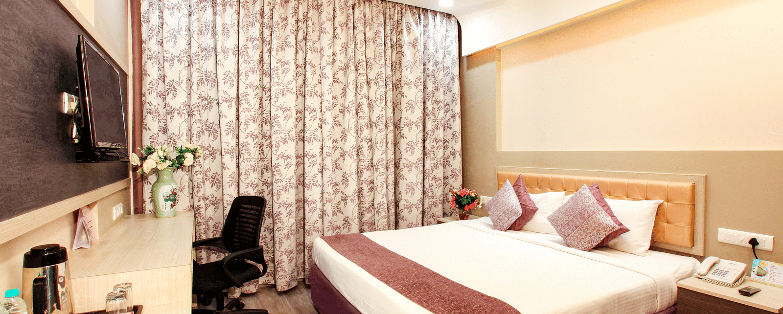 A well-appointed hotel room with a patterned headboard and modern amenities. - Tara, Comfort Hotel in Hyderabad - Ramoji Film City.