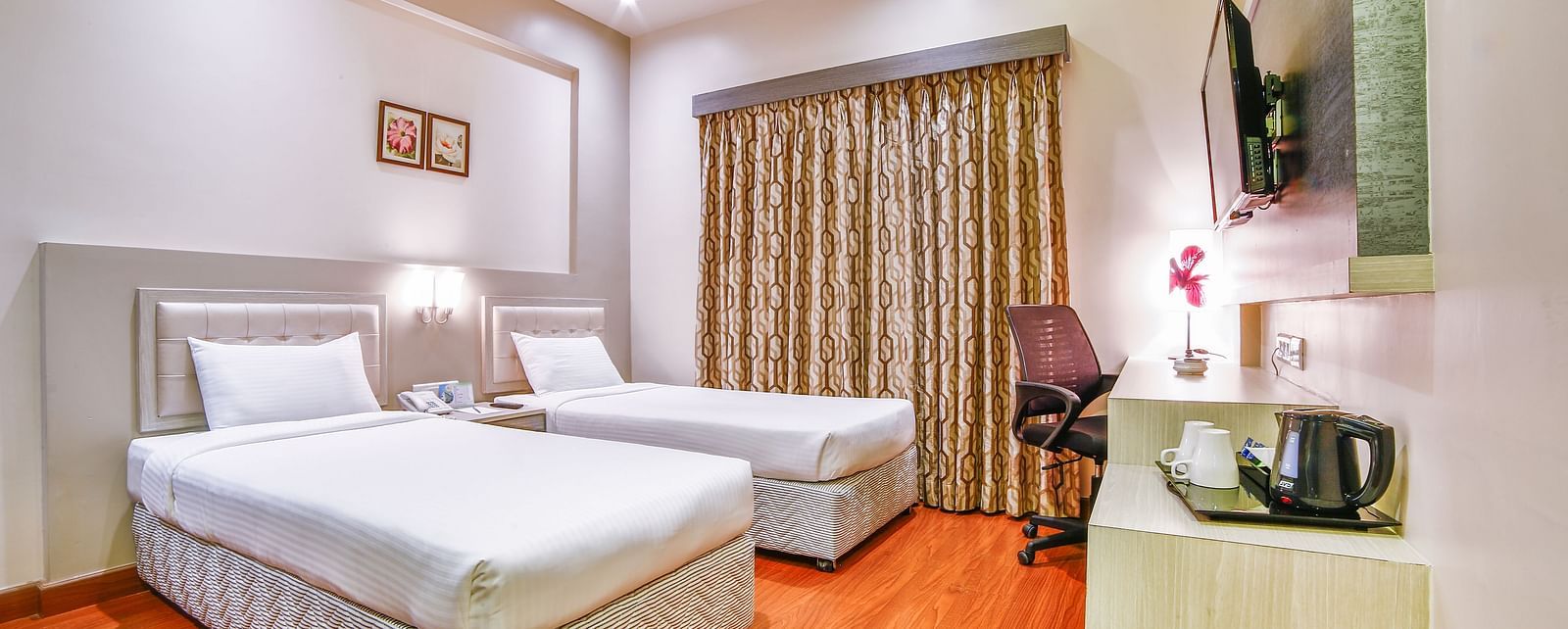 A neat hotel room with two large beds, a study desk, and ambient lighting. - Tara, Comfort Hotel in Hyderabad - Ramoji Film City.