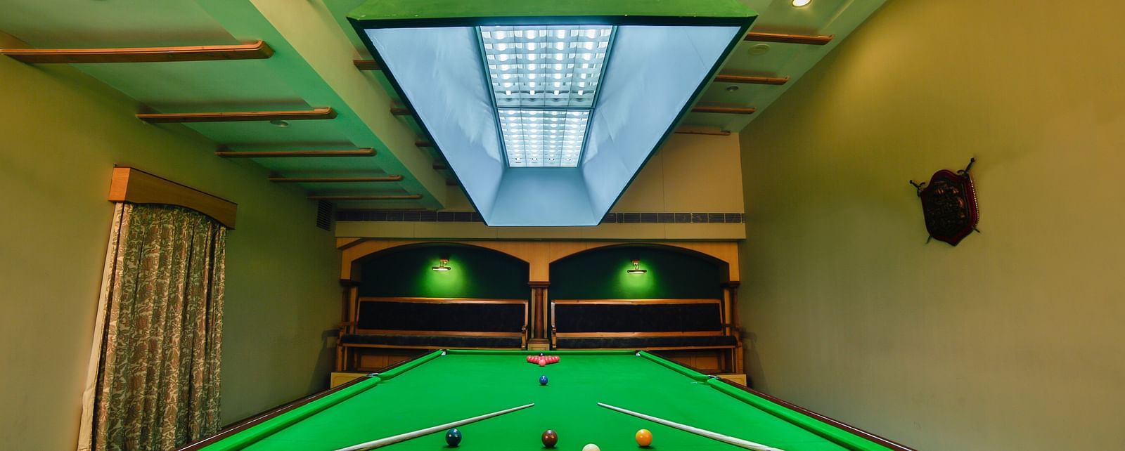 Pool table with billiards cue sticks placed at the corners at Tara, Comfort Hotel in Hyderabad - Ramoji Film City.
