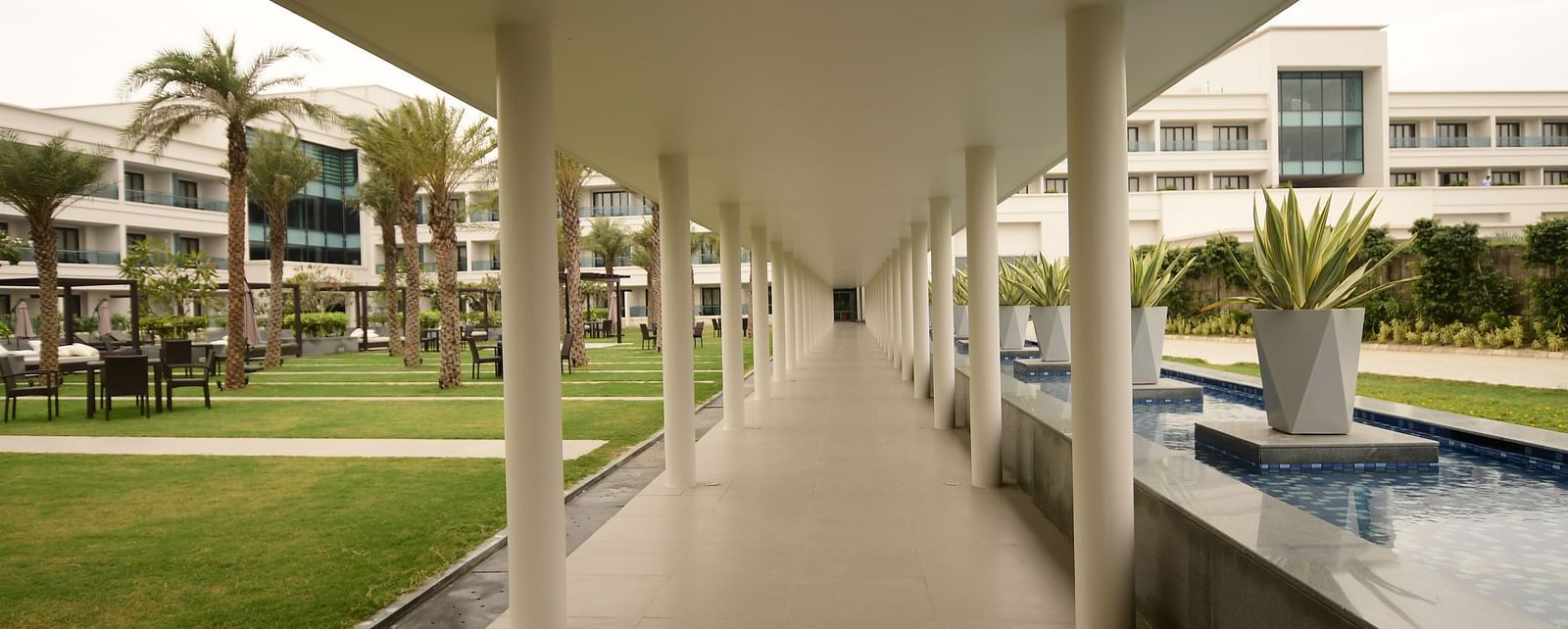 A corridor with pillars on both sides, featuring glass on one side and a small water fountain on the other