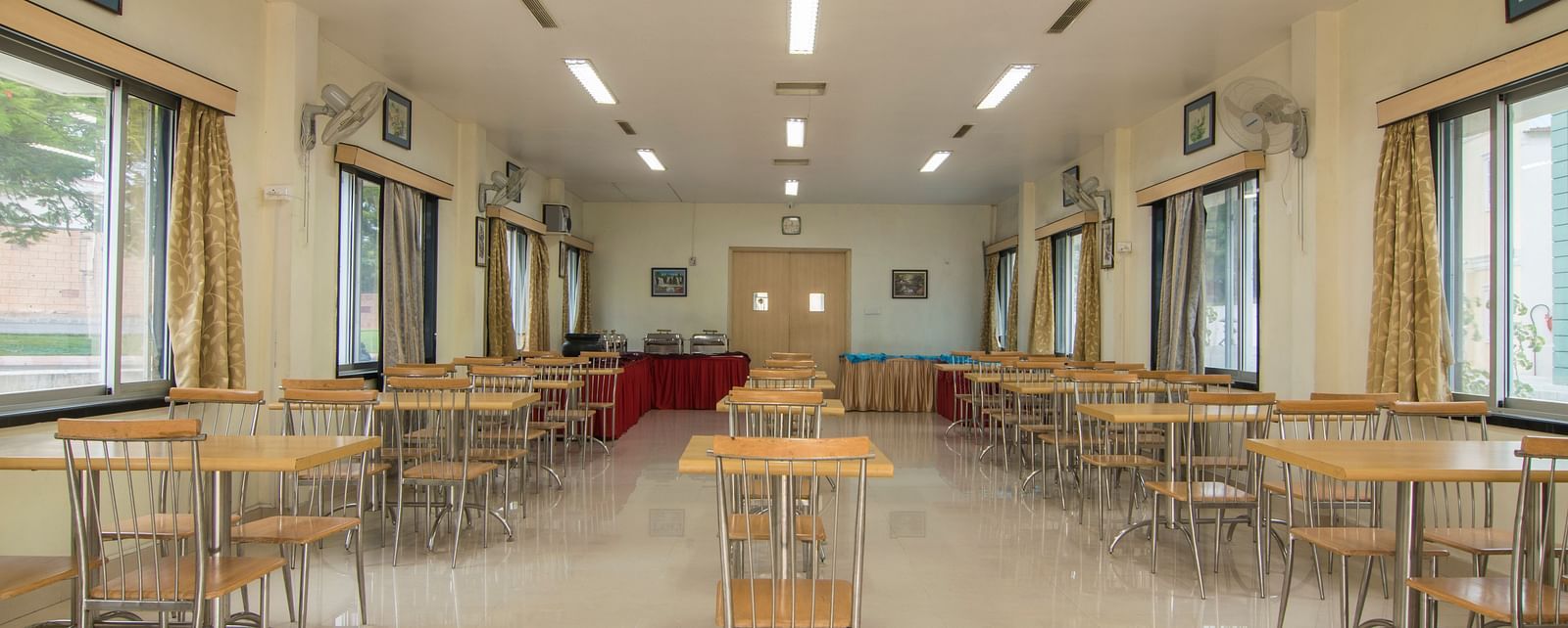 Another view of the same conference room, with a focus on the seating arrangement and lighting fixtures at Shantiniketan - Budget Stay in Hyderabad near Ramoji Film City.