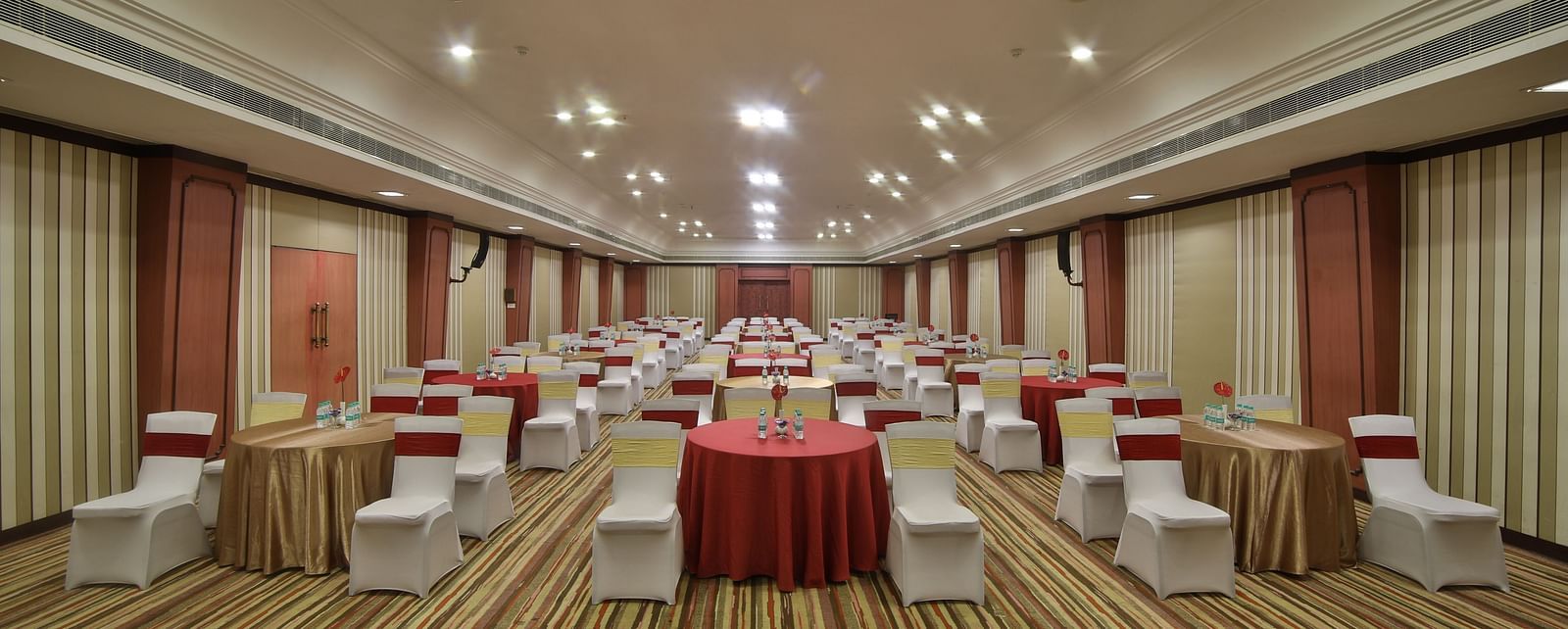  Seating arrangement in Terrace Hall A grand hotel suite with an opulent red and white decor, large bed, and seating area, reflecting a traditional style at Sitara Luxury Hotel in Hyderabad near Ramoji Film City.