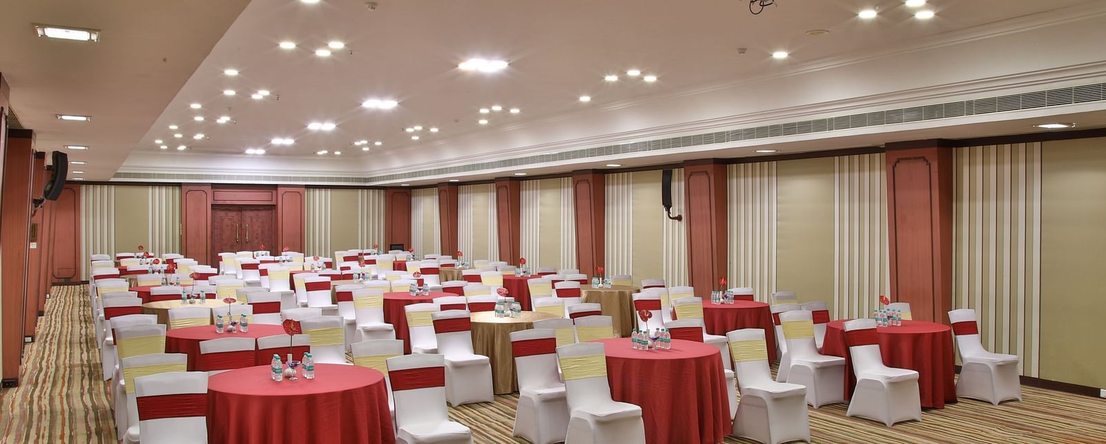  Seating arrangement in Terrace Hall A grand hotel suite with an opulent red and white decor, large bed, and seating area, reflecting a traditional style at Sitara Luxury Hotel in Hyderabad near Ramoji Film City.