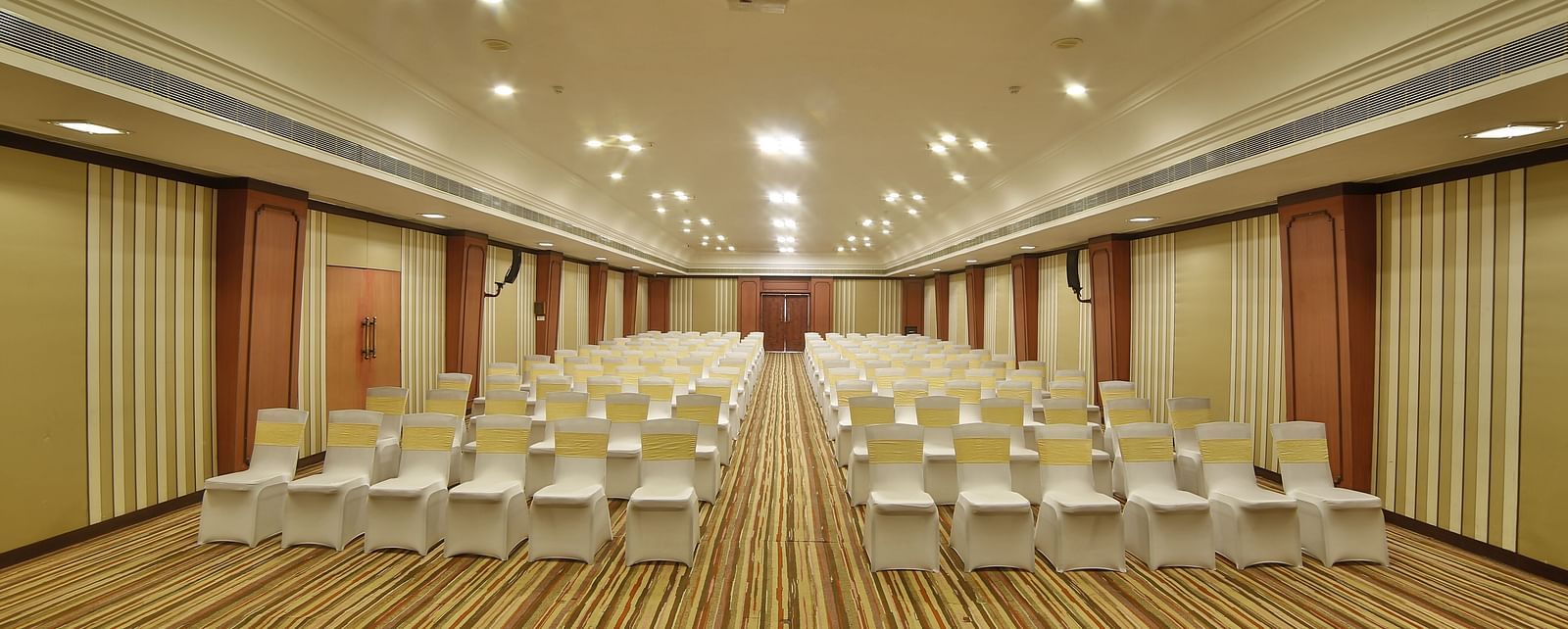 Seating arrangement in Terrace Hall A grand hotel suite with an opulent red and white decor, large bed, and seating area, reflecting a traditional style at Sitara Luxury Hotel in Hyderabad near Ramoji Film City.