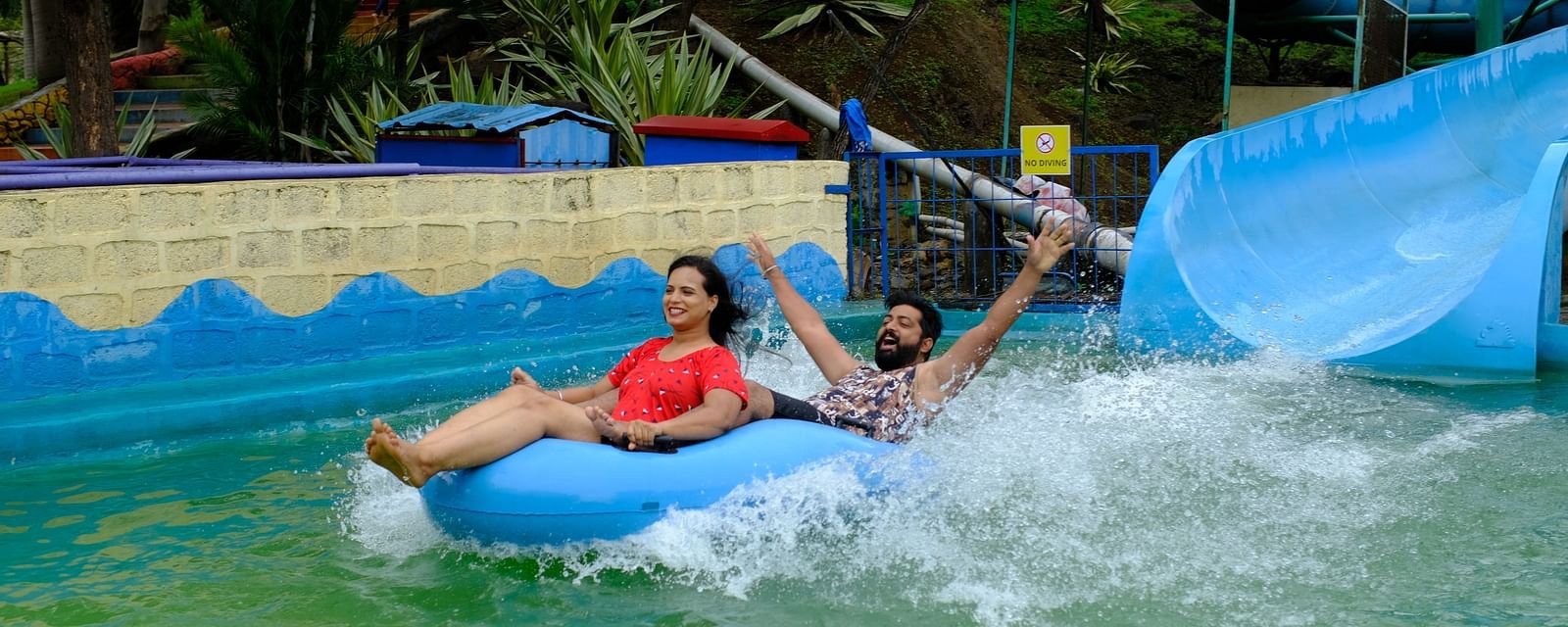 couple having fun on a water slide in a rubber raft at an adventure water park | Diamond Parks, Pune 