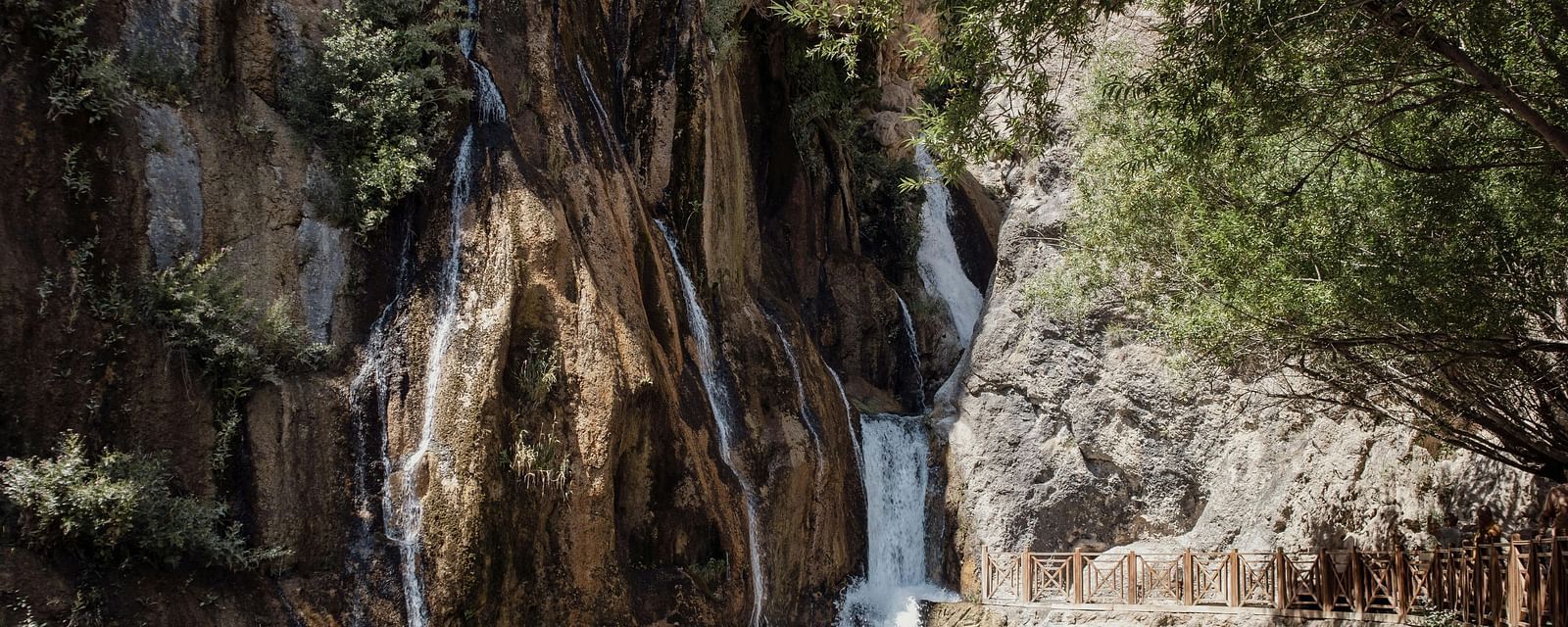 A view of waterfall passing by a rocky surface  on a sunny day.