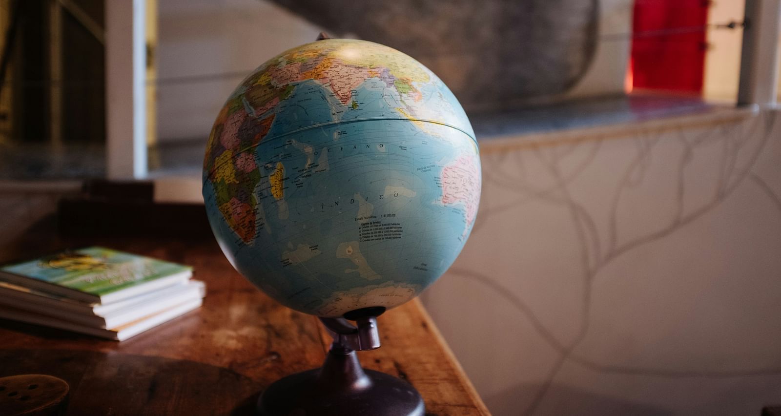 a globe kept on a table with books behind it