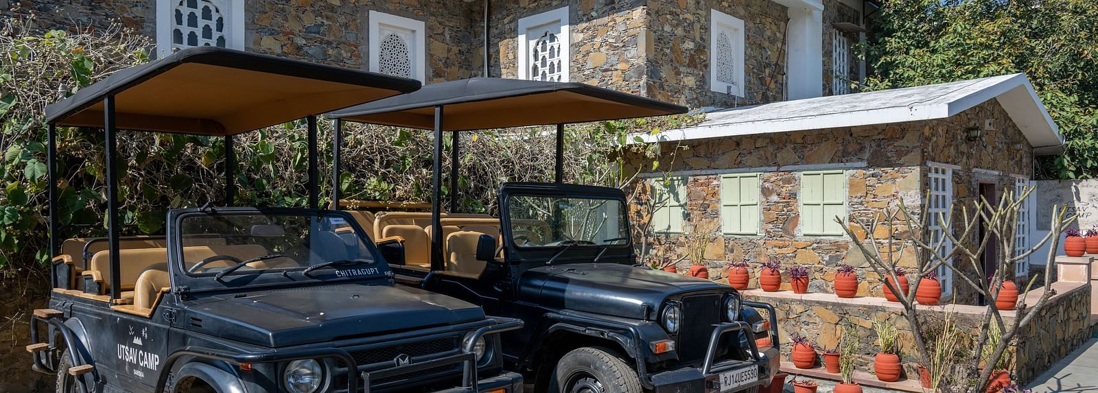 Two jeeps placed in front of a building made out of stone - Utsav Camp