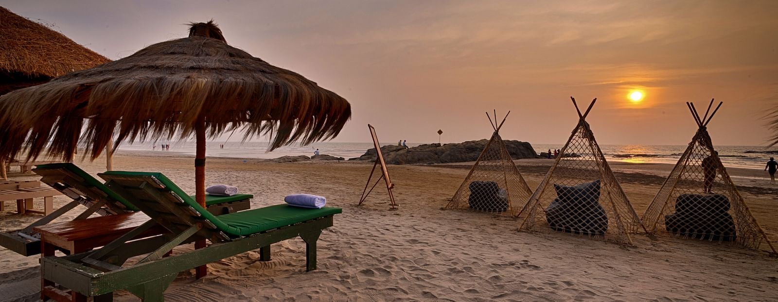 Beachfront view with loungers and teepee-style cabanas at Royale Amata by the Beach Restaurant