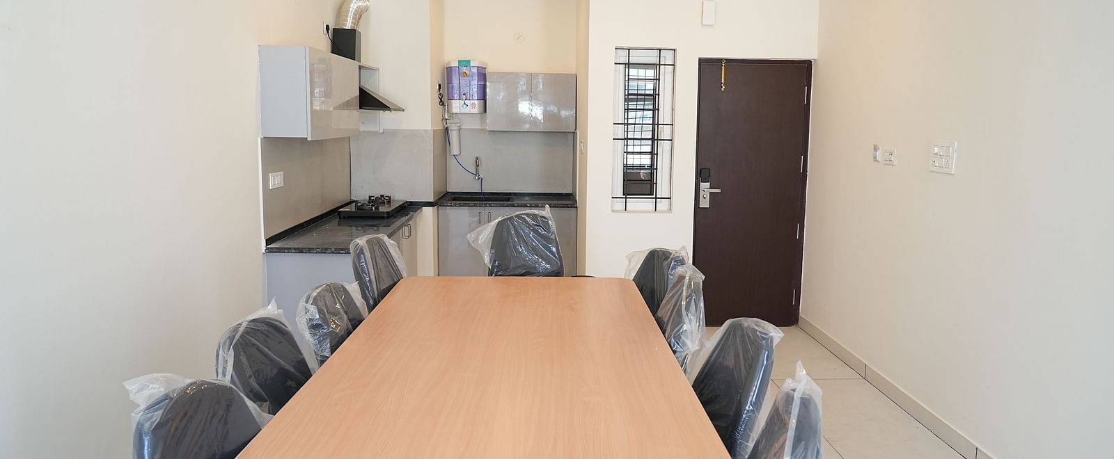 front view image of the dining area featuring the long dining table with the fully equipped kitchen in the background - Hotel Grand Sigma