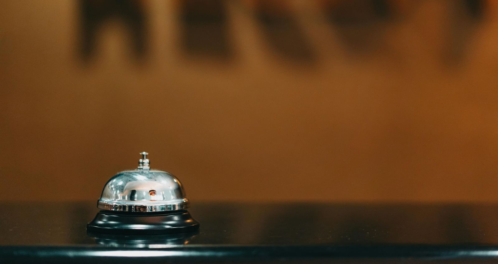 A service bell on a counter with blurred background, typically found at hotel reception or customer service desks.s-mikhail-nilov-7821343