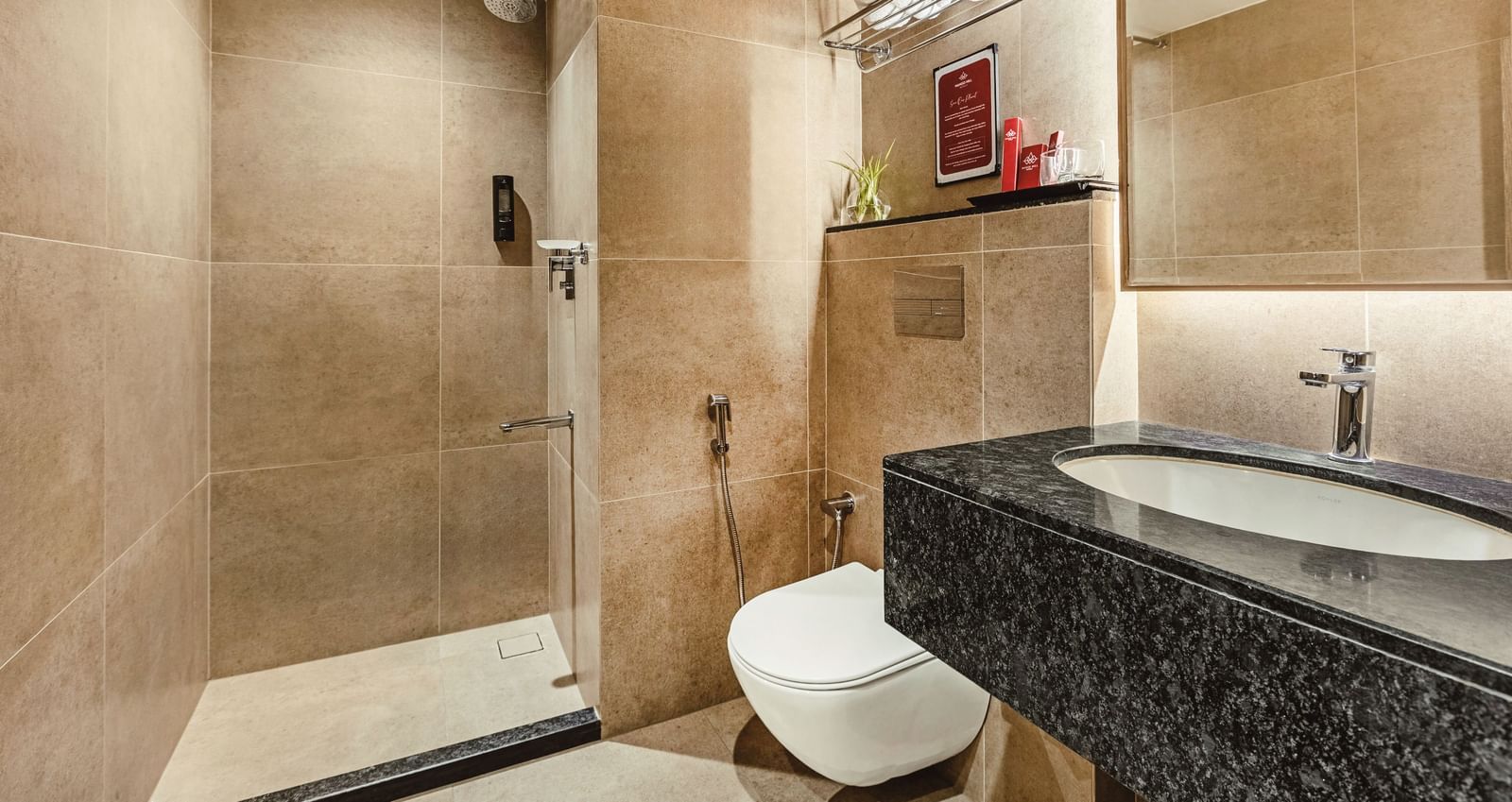 A bathroom at Mango Hill Central, Chennai, with a black-topped sink, toilet, and shower area visible.