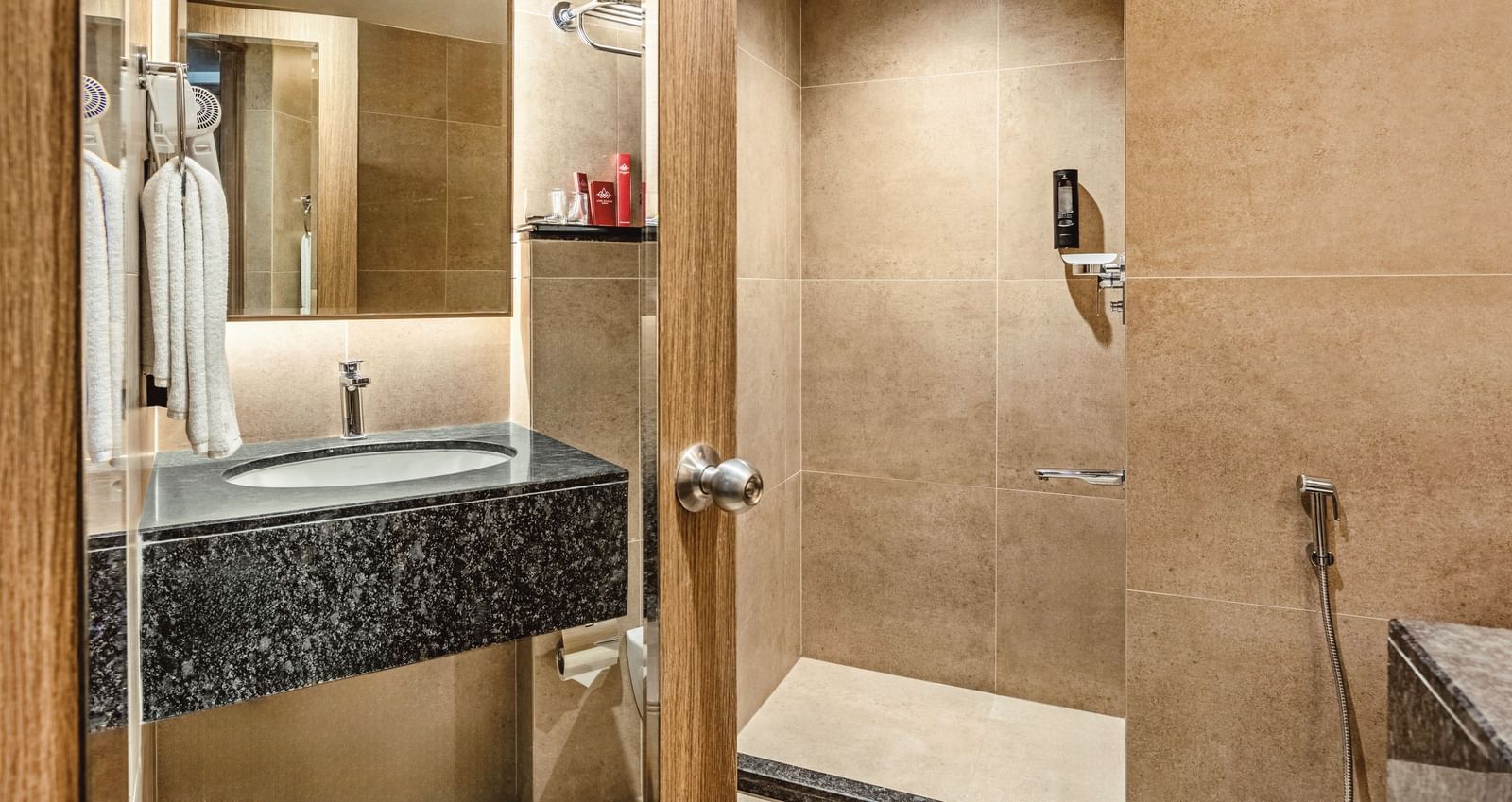  A close-up of the sink, mirror, and shower area in a bathroom at Mango Hill Central, Chennai.