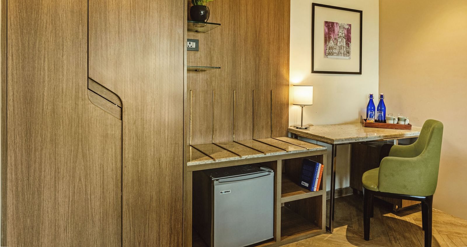 A room at Mango Hill Central, Chennai, with wooden cabinets, a desk, and a small refrigerator.