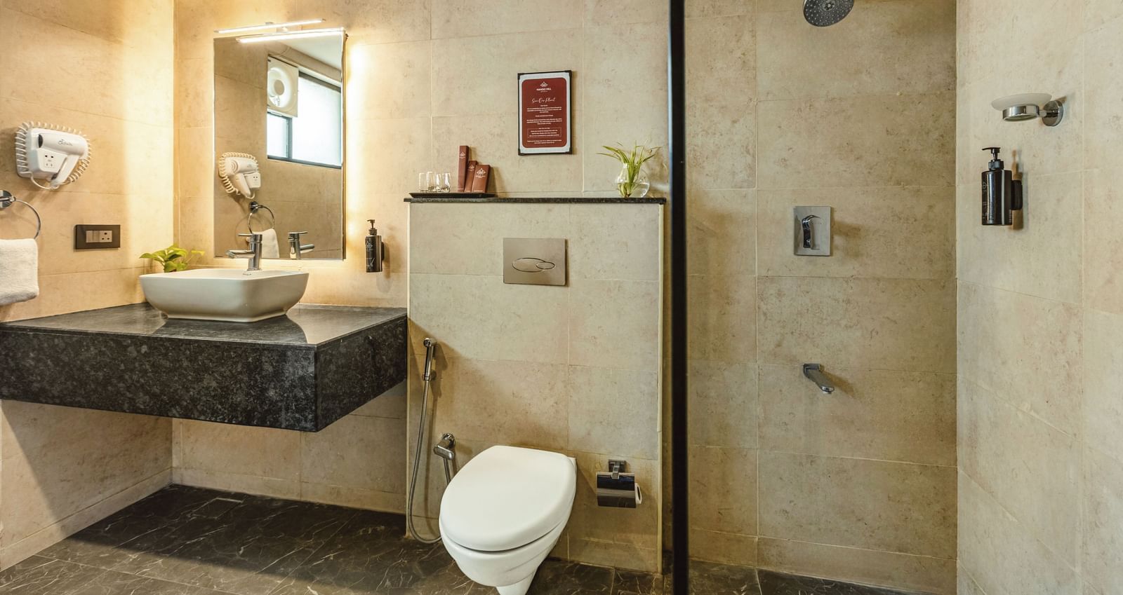 A bathroom at Mango Hill Central, Chennai, with a sink, a toilet, and a walk-in shower area.