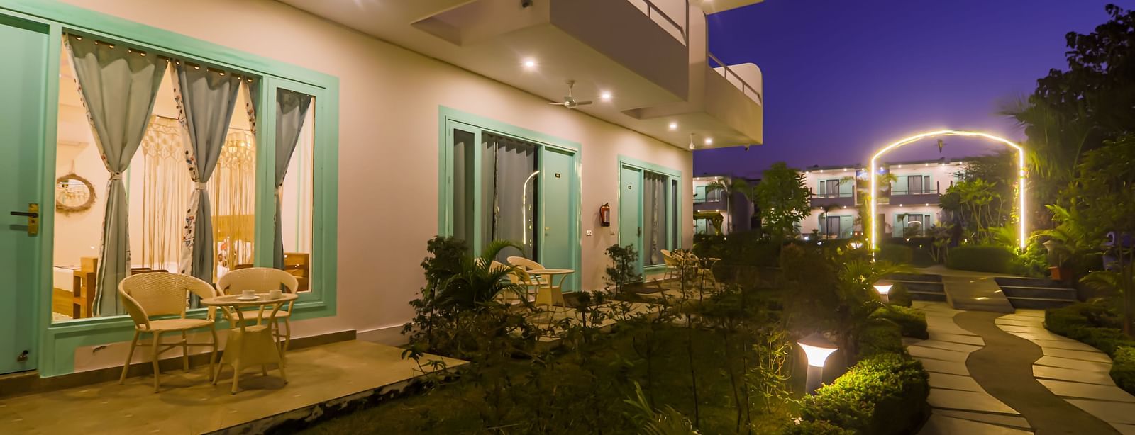Balconies of rooms at Vedikant Resorts The Mallard Corbett are lit up at night, overlooking the grounds.