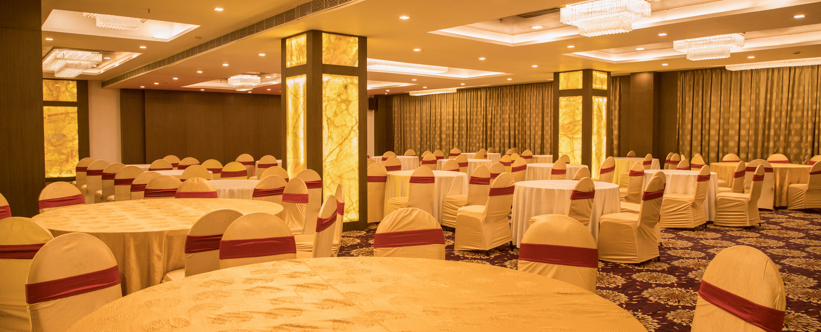 A large banquet hall at Benzz Park Chennai with multiple round tables and chairs, ready for a function.