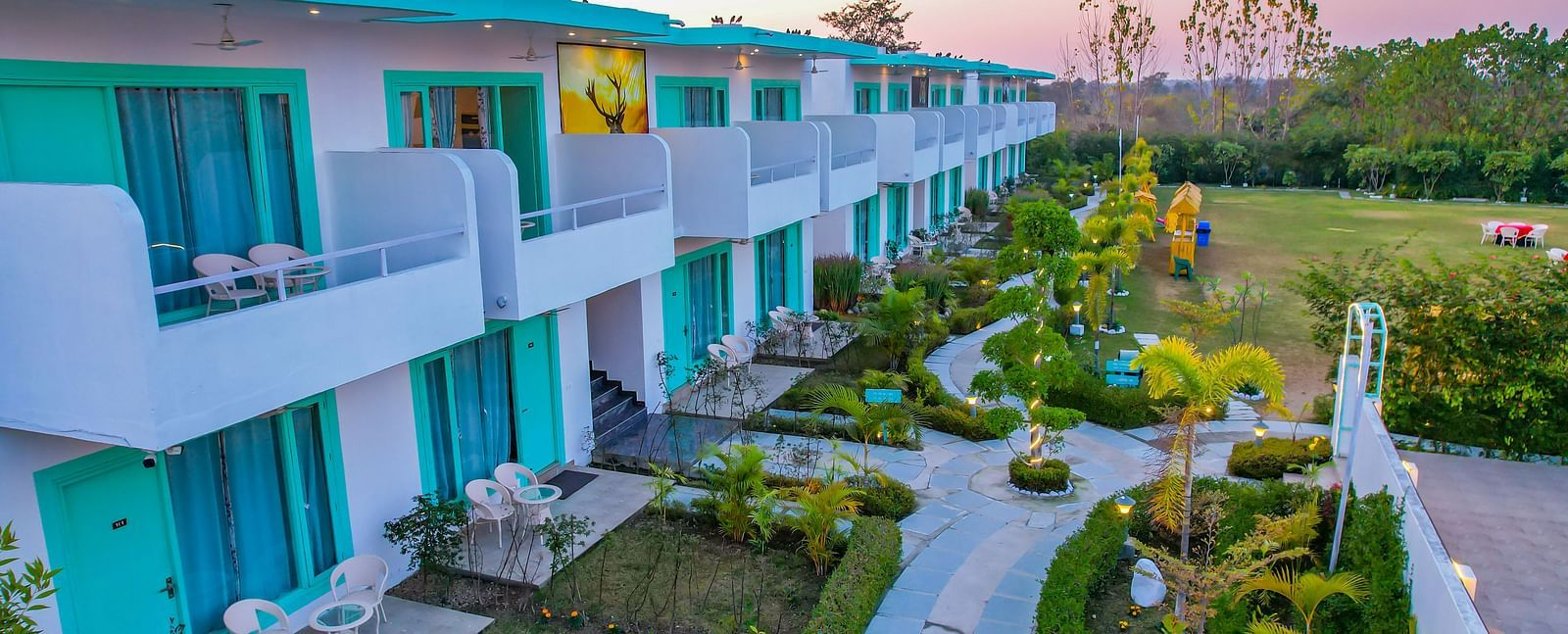 Curved pathway at Vedikant Resorts The Mallard Corbett surrounded by plants and lined with rooms on both sides.