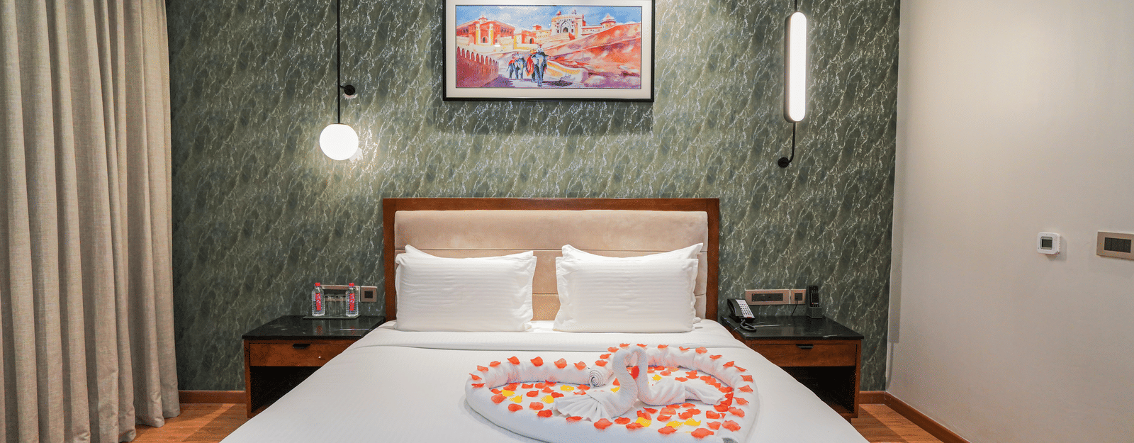 A room with a king size bed, featuring a heart made of rose petals on the duvet at Pushkara Resort & Spa.