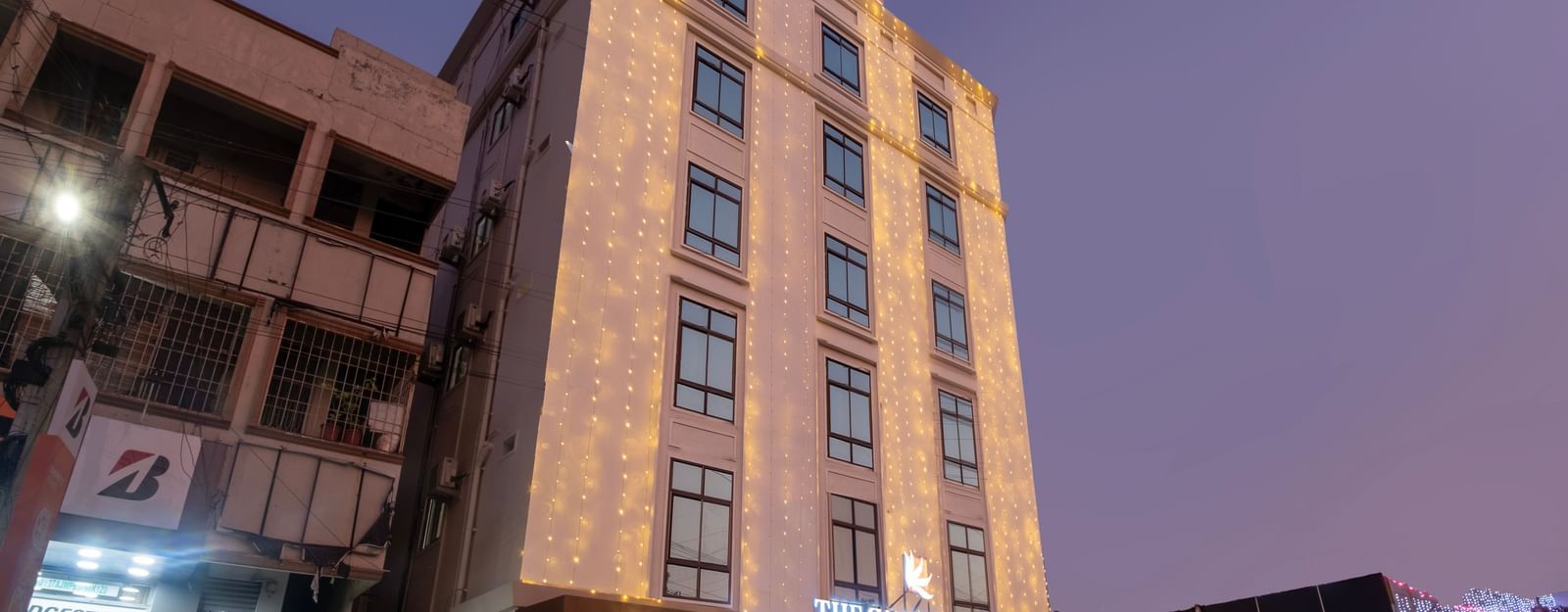 Evening exterior view of Swarna's The Capital with illuminated facade and welcoming entrance.