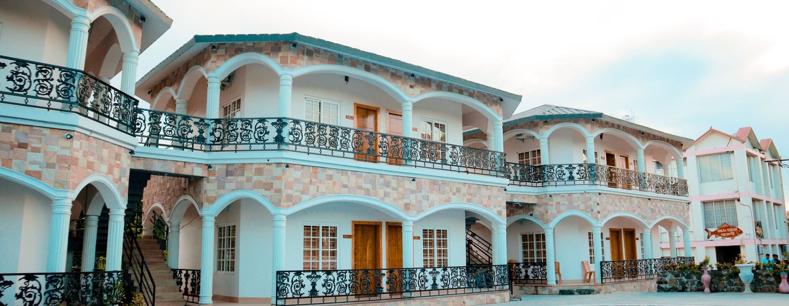 facade image of dip holidays in birbhum from a different angle featuring cyan coloured building with black metal railings