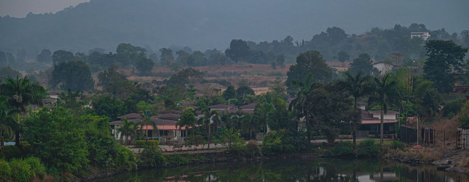 A serene view of a lake surrounded by trees and hills in the background at Lotus Leaf Boutique Hotel.