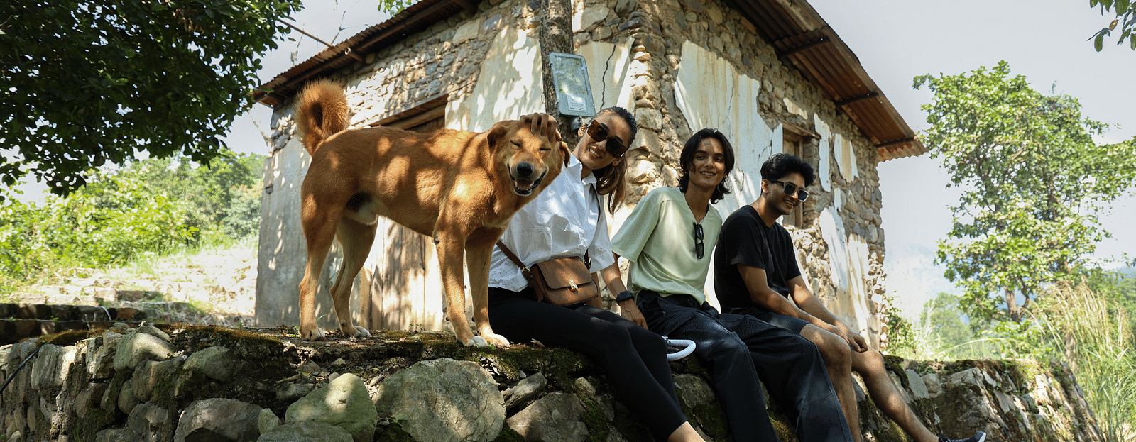 A dog sitting next to three people on a huge rock