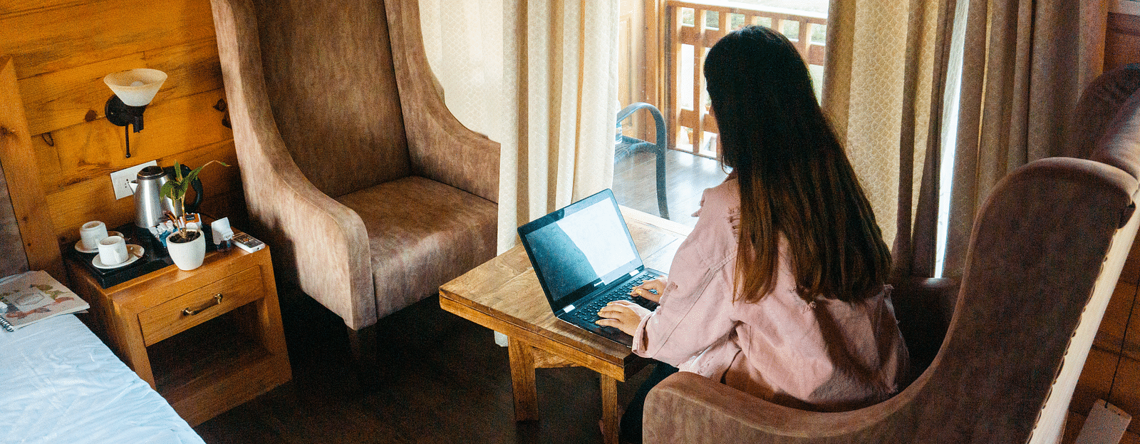 A woman working on her laptop at the Pinewood Cottage at the Sylvan Retreat, Dehradun.