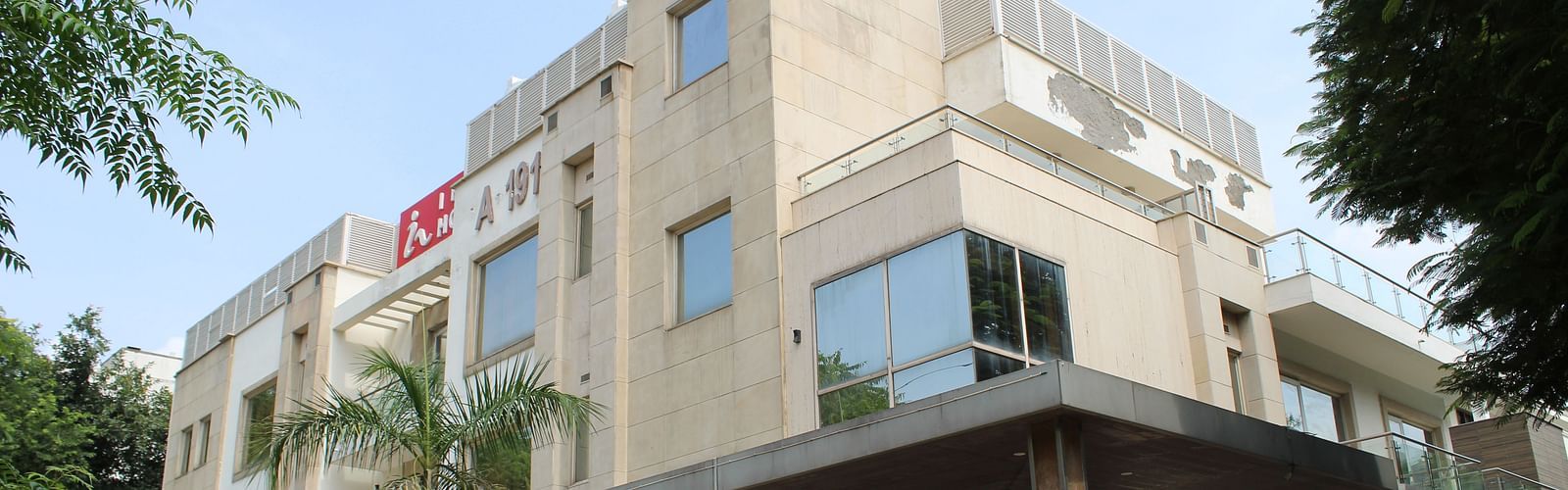 A facade image of Inde Hotels Vista Woods featuring a multi storey building surrounded by trees