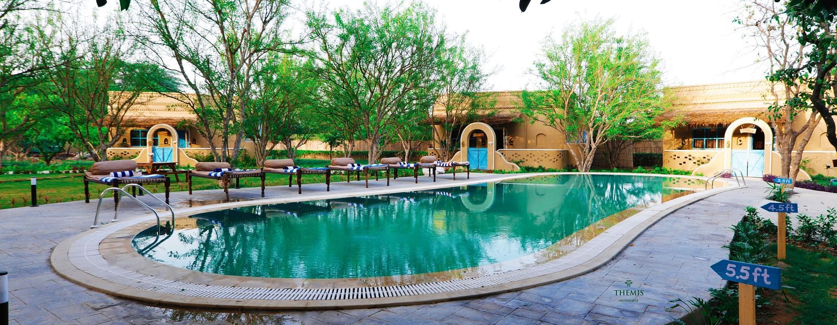 Swimming pool surrounded by trees at Themis Mudhouse - A Nature's Retreat Resort & Wellness