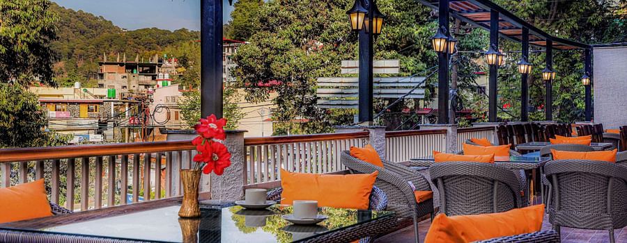 A rooftop dining area with scenic mountain views, decorated with stylish chairs and tables - Vinsober Monal, Nainital